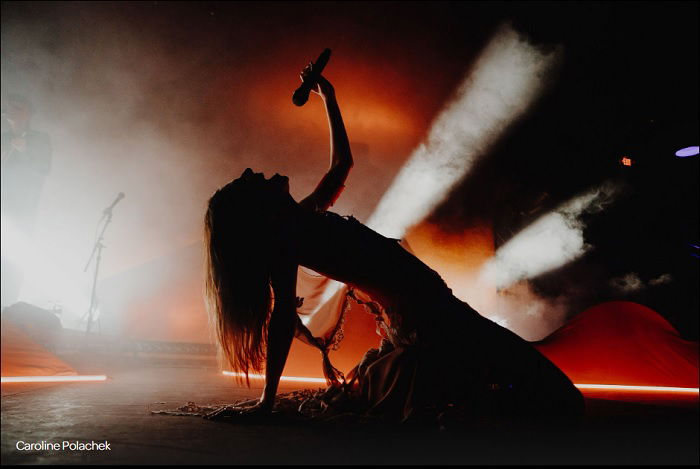 Female singer on her knees bending back while singing